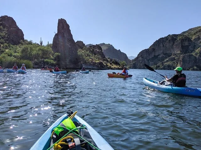 Group of kayakers on a lake surrounded by desert hills and rock formations