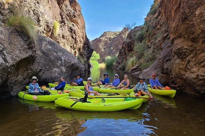 A group of women in kayaks gathered together in a rocky canyon