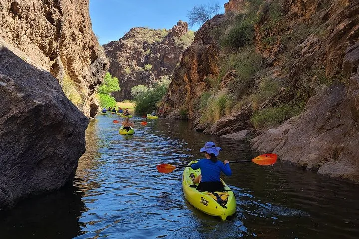A group of people kayaking through a narrow, rocky canyon