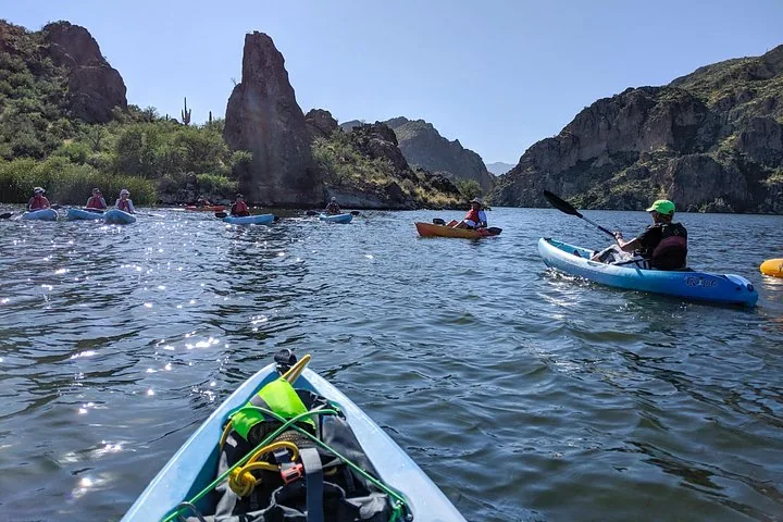 A group of people kayaking on a lake with rocky shores