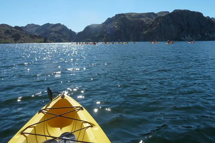 View from a yellow kayak looking toward a group of kayakers and mountains